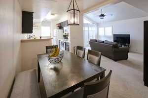 Dining area with light colored carpet, plenty of natural light, ceiling fan, and vaulted ceiling