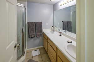 Full bathroom with a stall shower, double vanity, and light tile patterned floors
