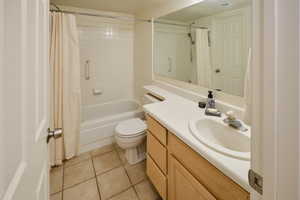 Full bath with vanity, light tile patterned floors, and shower / bath combination with curtain