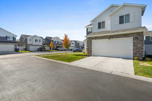 Traditional-style home featuring a residential view, stone siding, driveway, and an attached garage