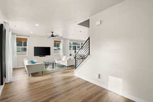 Living room with light wood-type flooring, recessed lighting, stairs, a ceiling fan, and a textured ceiling