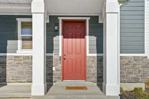 Property entrance with stone siding and a porch