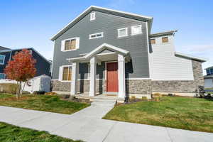 View of front facade featuring stone siding and a front yard