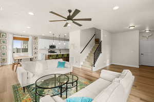 Living room with stairway, recessed lighting, light wood-type flooring, and ceiling fan