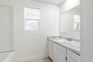 Full bath featuring vanity, a tub to relax in, plenty of natural light, and light tile patterned floors