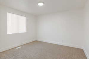Empty room featuring light carpet and baseboards