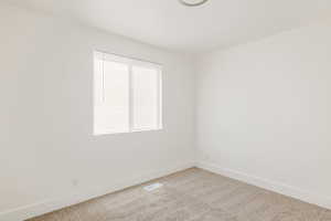 Spare room featuring light colored carpet and baseboards
