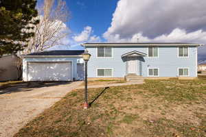 View of front of house featuring concrete driveway, a garage, and a front yard