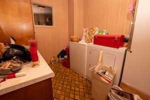 Laundry area featuring independent washer and dryer and wood walls