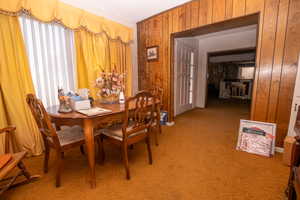 Dining space with wooden walls and light colored carpet