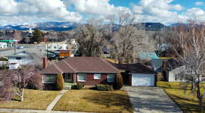 View of front of house with a mountain view, a front lawn, driveway, and a chimney
