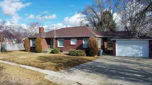 Ranch-style house featuring a chimney, brick siding, driveway, and a garage