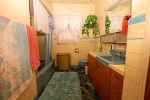 Bathroom featuring tile walls, vanity, shower / tub combo with curtain, and a wainscoted wall