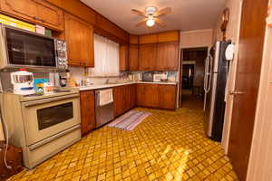 Kitchen with brown cabinetry, light countertops, stainless steel appliances, and a ceiling fan