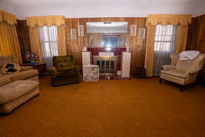 Sitting room with a fireplace, carpet flooring, a textured ceiling, and wooden walls