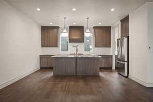 Kitchen featuring high end fridge, pendant lighting, dark brown cabinetry, dark wood-style floors, and custom range hood