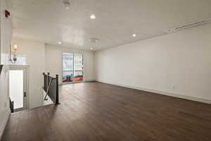 Unfurnished living room featuring recessed lighting, a textured ceiling, and dark wood-style floors
