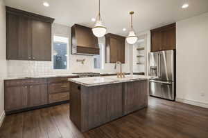 Kitchen featuring dark brown cabinetry, high quality fridge, hanging light fixtures, tasteful backsplash, and open shelves