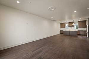 Unfurnished living room featuring recessed lighting, dark wood-type flooring, and a textured ceiling