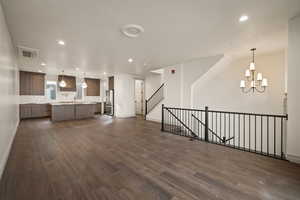 Unfurnished living room with recessed lighting, dark wood-style flooring, a chandelier, and stairs