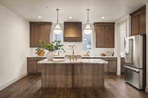 Kitchen with stainless steel appliances, decorative light fixtures, light stone countertops, dark wood-style flooring, and decorative backsplash