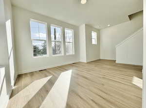 Unfurnished living room with light wood-style floors and baseboards