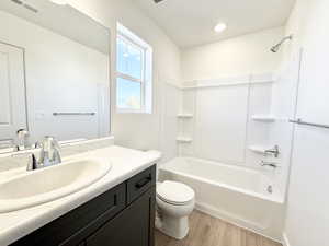 Bathroom with bathtub / shower combination, vanity, and light wood finished floors