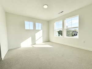 Carpeted empty room featuring a textured ceiling and healthy amount of natural light