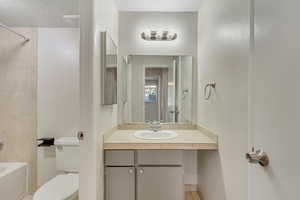 Bathroom with vanity, shower / bath combination, and a textured ceiling