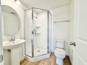 Bathroom featuring a stall shower, light wood-style flooring, and a textured ceiling