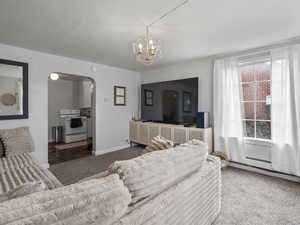 #37 (Upstairs 2-bedroom): Carpeted living area featuring arched walkways, a baseboard radiator, and plenty of natural light