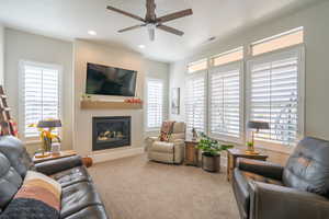Carpeted living room featuring a glass covered fireplace, a ceiling fan, plenty of natural light, and recessed lighting