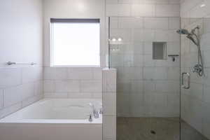 Bathroom featuring a garden tub, a shower stall, and healthy amount of natural light