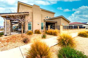 Back of property with a fenced front yard, stucco siding, and a patio area