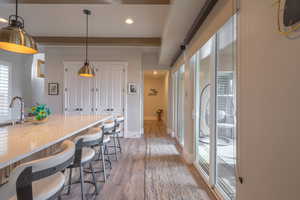 Kitchen with pendant lighting, a kitchen breakfast bar, light wood finished floors, light stone countertops, and recessed lighting