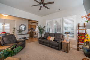 Carpeted living room featuring a ceiling fan and a chandelier