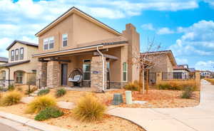 View of front of property with stucco siding, a chimney, and stone siding