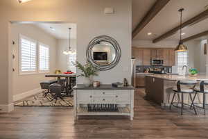 Kitchen featuring a breakfast bar area, decorative backsplash, brown cabinets, a chandelier, and dark wood-style floors