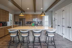 Kitchen with decorative light fixtures, tasteful backsplash, dark wood-style floors, stainless steel appliances, and a large island