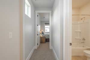 Hall featuring light colored carpet and baseboards