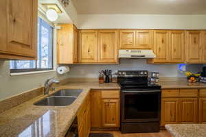 Kitchen featuring electric stove, light stone countertops, under cabinet range hood, light wood finished floors, and dishwasher