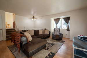 Living area with stairway, light wood finished floors, and a ceiling fan