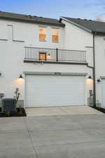 View of front of property featuring stucco siding, driveway, a balcony, and a shingled roof