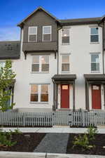 Traditional-style house with stucco siding and a fenced front yard