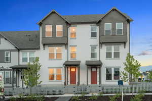 Traditional home with a shingled roof, stucco siding, and a fenced front yard