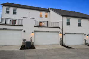 Back of house featuring a balcony, stucco siding, concrete driveway, an attached garage, and a shingled roof