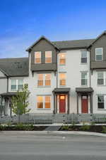 Traditional-style home featuring a shingled roof, stucco siding, and a fenced front yard