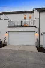 View of front of house featuring a balcony, stucco siding, driveway, and a garage