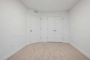 Unfurnished bedroom featuring light colored carpet and a closet