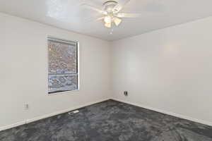 Unfurnished room with dark carpet, ceiling fan, and a textured ceiling